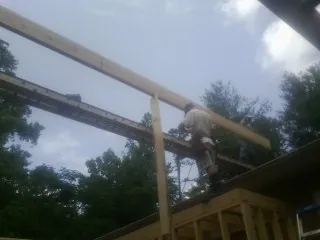 Carpenter setting a ridge beam over a new addition frame — Ice Dam Removal by Roofing Brothers in Yoder