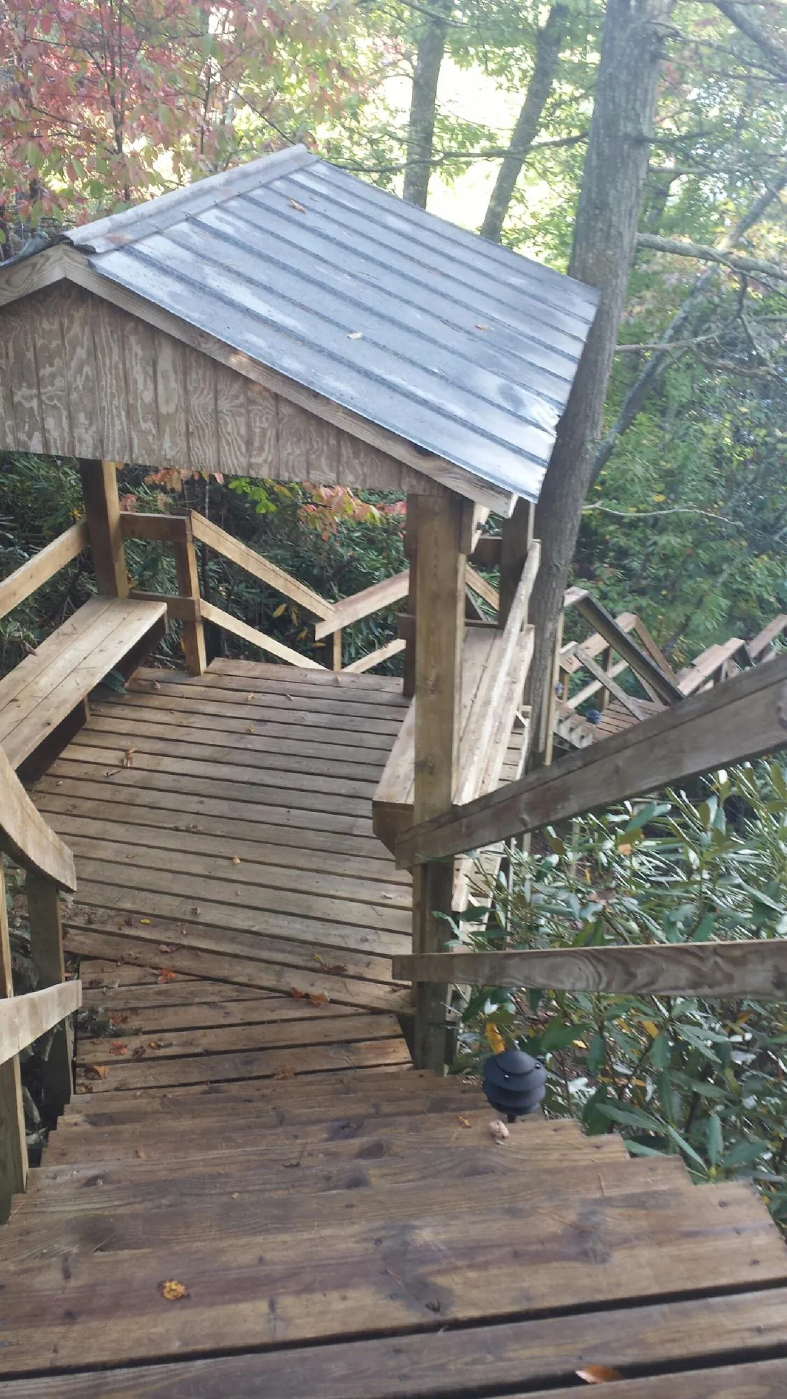 Metal roofed shelter over wooden steps on a wooded walkway — Skylight Repair & Installation work by our crew in Yoder