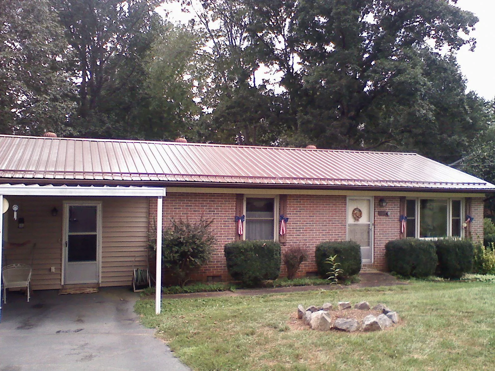 Bronze metal roof and carport on a brick ranch home — Roof Repair work by our crew in Yoder